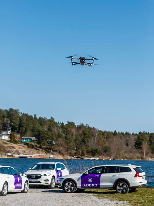 Tre bilar från Addici och en drönare i luften ovanför.