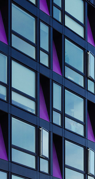 En vägg på en lila byggnad med många fönster.