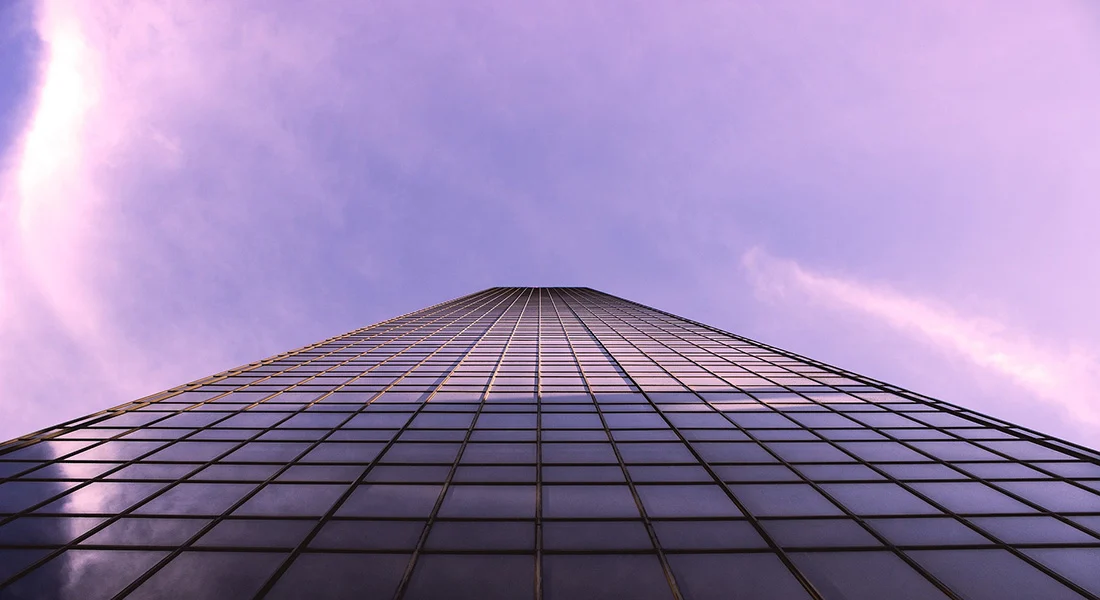 En fastighet med glasväggar mot en lilatonad bakgrund