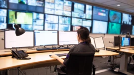 en medarbetare framför en vägg av bildskärmar på Addicis larmcentral