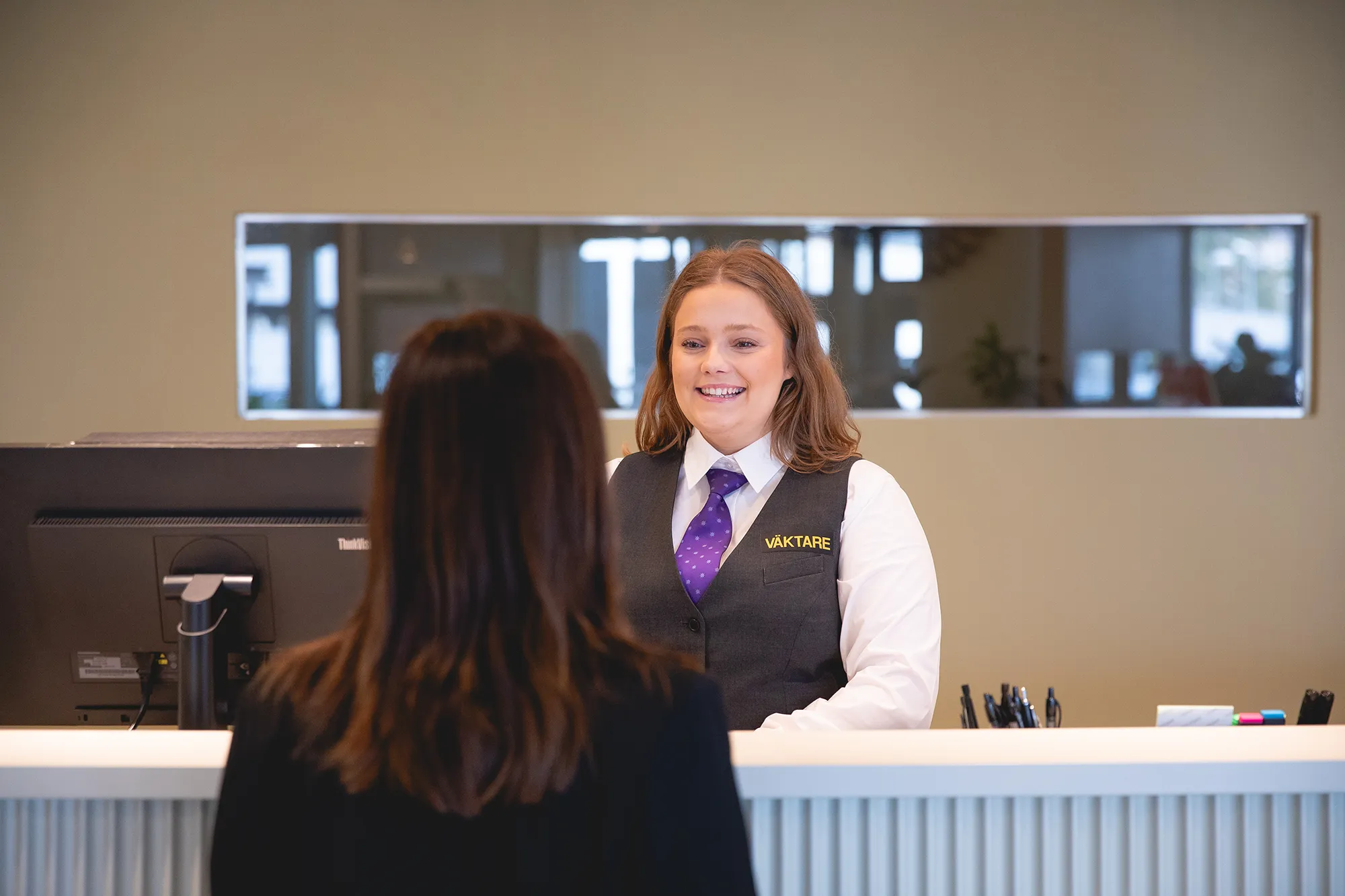 En väktarreceptionist från Addici bakom en receptionsdisk