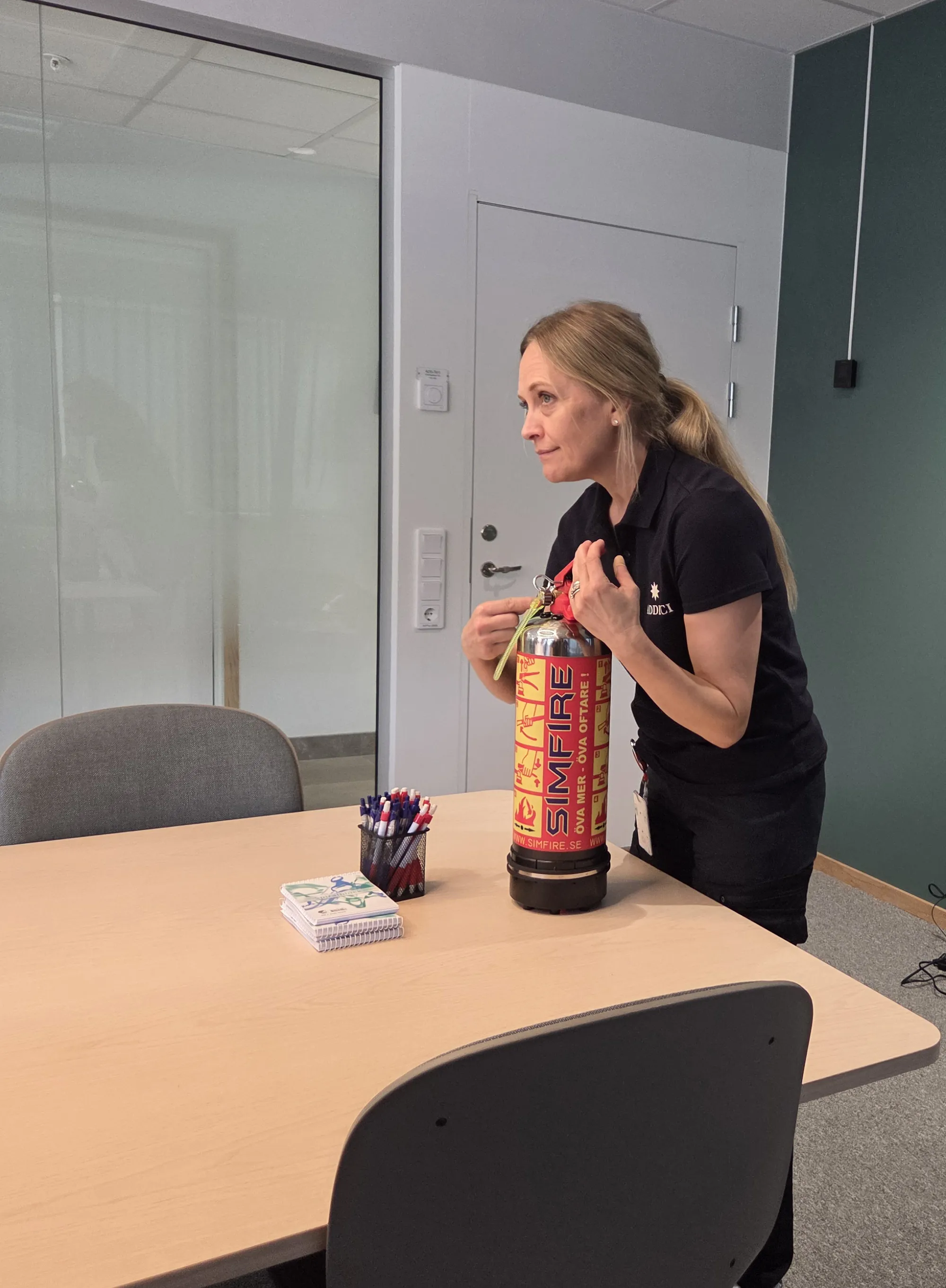En medarbetare från Addici går igenom hur brandsläckaren fungerar i ett mötesrum