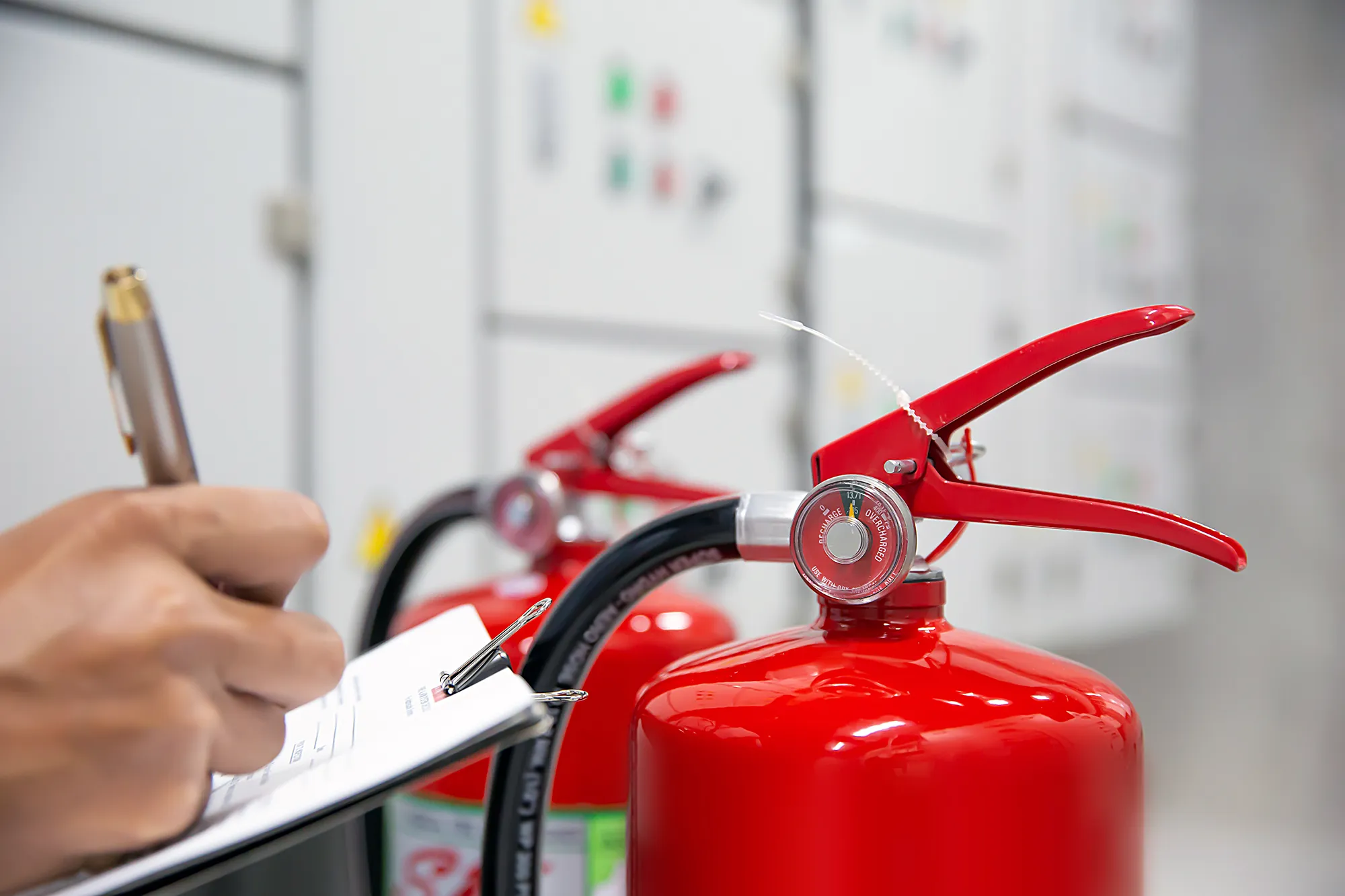 Närbild av händer som fyller i ett dokument framför en brandsläckare